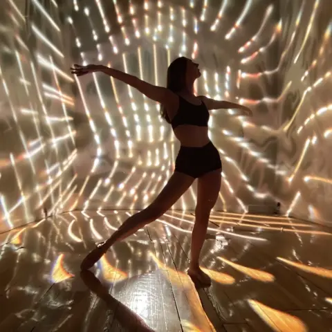 „a photo of a dancer with the stage lights creating dynamic shadows and reflections“